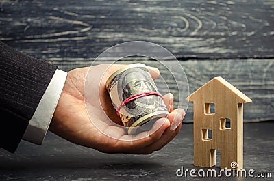 Wooden house and money in hand. A loan secured by real estate. Home renovation and repair. Warm loans. Buying and selling homes. A Stock Photo