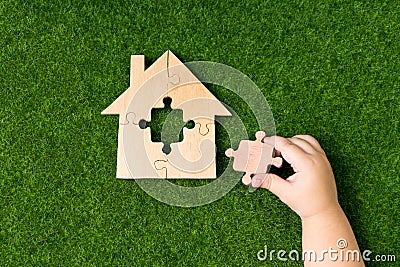 Wooden house of puzzles, the missing element in the hands Stock Photo
