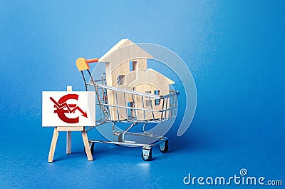 Wooden houses in a shopping cart and an easel with a red euro arrow down chart. Low sales. Value cost decrease. Bad attractiveness Stock Photo