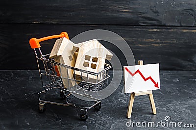 Wooden houses in a supermarket cart and up down. Reduction of demand for housing and real estate. The concept of falling prices Stock Photo