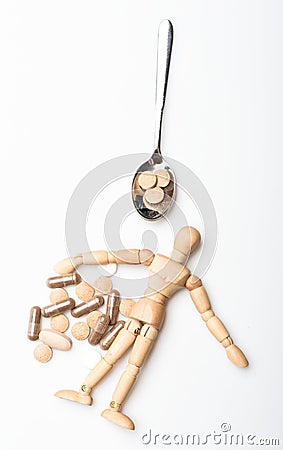 Wooden human dummy near spoon full pills and tablets. Take medicine concept. Health and treatment. Health care and Stock Photo
