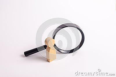 A wooden human figure stands near a magnifying glass Stock Photo