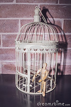 Wooden Human Manikin locked inside a white ornamental bird cage Stock Photo