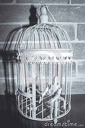 Wooden Human Manikin locked inside a white ornamental bird cage Stock Photo