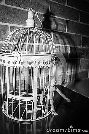 Wooden Human Manikin locked inside a white ornamental bird cage Stock Photo