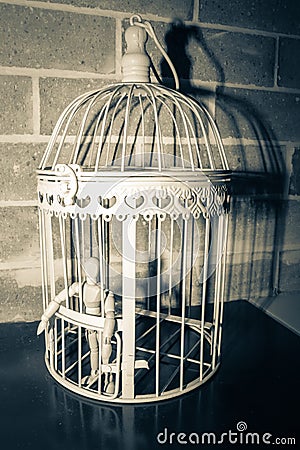 Wooden Human Manikin locked inside a white ornamental bird cage Stock Photo