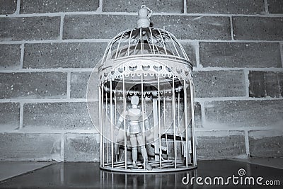 Wooden Human Manikin locked inside a white ornamental bird cage Stock Photo