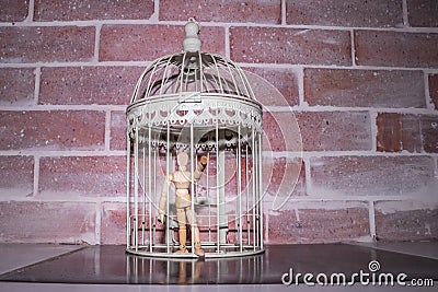 Wooden Human Manikin locked inside a white ornamental bird cage Stock Photo