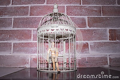 Wooden Human Manikin locked inside a white ornamental bird cage Stock Photo