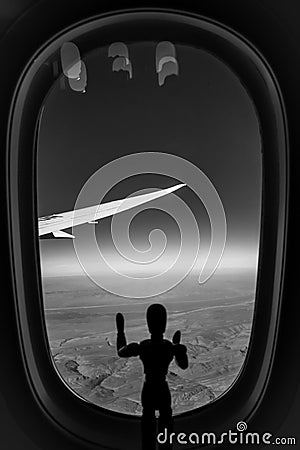 A Wooden Human Manikin standing looking through an airplane window at the landscape below Stock Photo