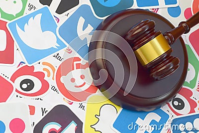 Wooden judge gavel lies on many paper logos of popular social networks and internet resources. Entertainment lawsuit concept Editorial Stock Photo