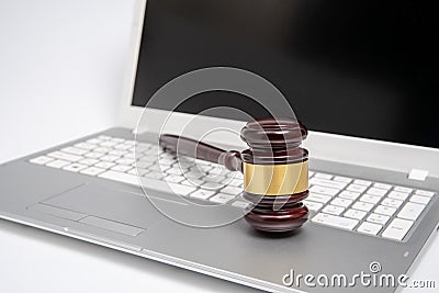 Wooden judge gavel on a silver laptop computer, cyber law or online auction concept. Stock Photo