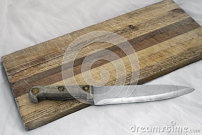 Wooden knife on grainy old fashioned cutting board Stock Photo