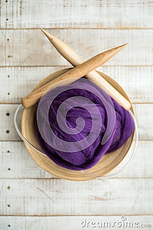 Wooden knitting needles and purple merino wool ball in a basket Stock Photo