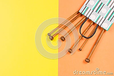 Wooden knitting needles on yellow and orange background Stock Photo