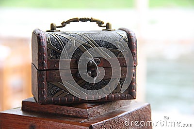 A wooden little chest of brown color, an ancient lock and a metal handle. Service concept small box for tips. Stock Photo