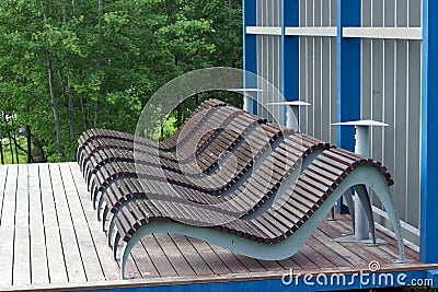 Wooden loungers under a shady tree in the park Stock Photo