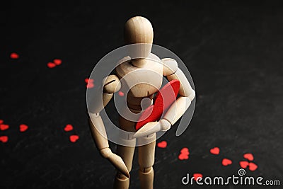 Wooden man with a red heart in his hands. Love time Stock Photo