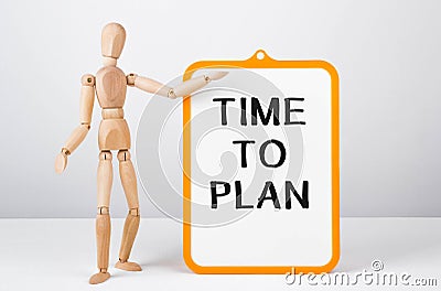 Wooden man shows with a hand to white board with text Time to plan Stock Photo