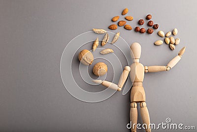 Wooden mannequin juggling nuts on gray pastel background. copy space Stock Photo