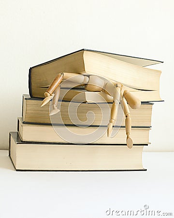 Wooden mannequin manikin student fell under pressure and was killed, crush studying and learning by bunch of books. Stock Photo