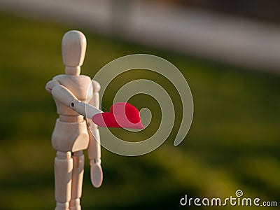 Wooden mannequin with a red heart on his hands Concept of romanticism and love Stock Photo