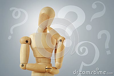 Wooden mannequin in thinking pose with quesion marks - Concept of question thinking and doubts Stock Photo