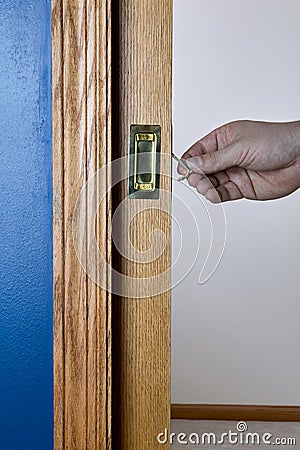 Pocket door by blue wall being unlocked and opened Stock Photo