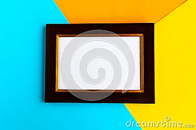 Wooden mockup vintage photo frame on bright geometric blue, orange and yellow background. Copy space for the text. Stock Photo