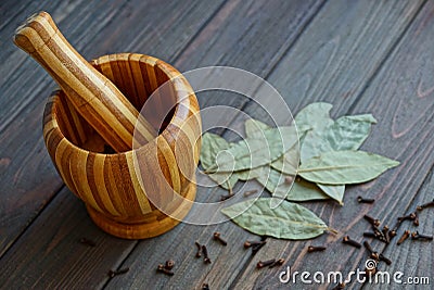 A wooden mortar round pepper and a bay leaf on a table Stock Photo
