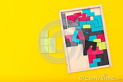 Wooden multicolored puzzle on yellow background. Flat lay Stock Photo