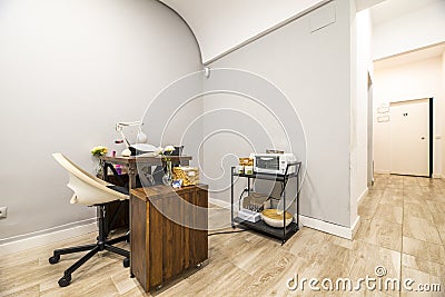 Wooden nail salon table with swivel chair with black leg and white synthetic seat with wood-like tile flooring Stock Photo