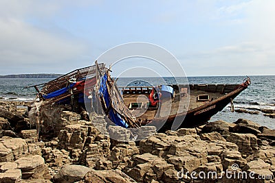 Wooden North Korean fishing boats thrown by a storm onto a rocky shore near Vladivostok Editorial Stock Photo