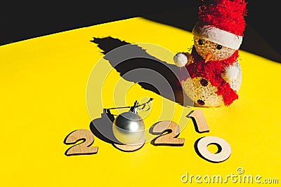 Wooden numbers 2021 chainging 2020, snowman and a silver christmas ball on a yellow background. Stock Photo