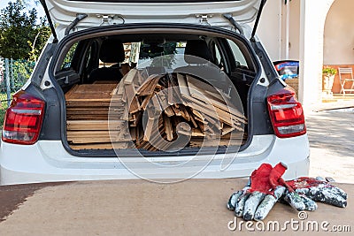 Wooden panels loaded into rear of white car with red workmans gloves in the foregorund Stock Photo