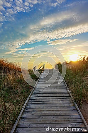 Wooden path at Baltic sea over sand dunes with ocean view, sunset summer evening Stock Photo