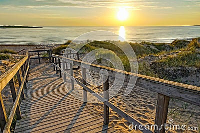 Wooden path at Baltic sea over sand dunes with ocean view, sunset summer evening Stock Photo