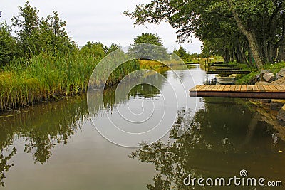 A wooden pier bridge over a river that goes into the distance along the reeds. A scene of calm pacified village life Stock Photo