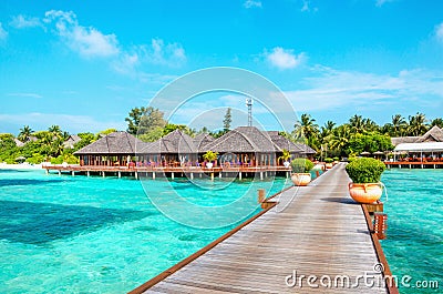 Wooden pier and exotic bungalow on the background of a sandy beach with tall palm trees, Maldives Editorial Stock Photo