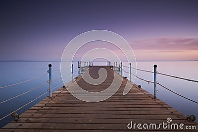 Wooden pier or jetty on sea sunset and sky reflection water. Long exposure, Dahab, Egypt Stock Photo