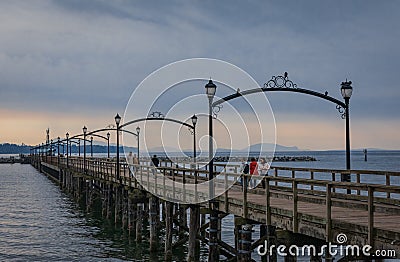 Wooden pier at White Rock, BC, Canada extends diagonally into image. City of White Rock Pier at overcast cloudy day Editorial Stock Photo