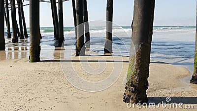 Wooden piles under pier in California USA. Pilings, pylons or pillars below bridge. Ocean waves tide Stock Photo