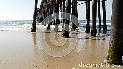 Wooden piles under pier in California USA. Pilings, pylons or pillars below bridge. Ocean waves tide Stock Photo