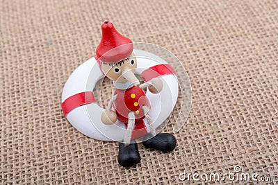 Wooden Pinocchio doll tied to a life saver Stock Photo