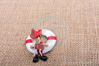 Wooden Pinocchio doll tied to a life saver Stock Photo