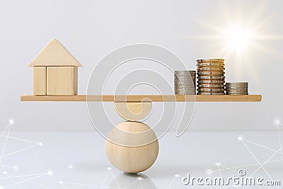 Wooden plank balancing of wood home and coins money comparison of income control expense with light effect graphic. Property inves Stock Photo