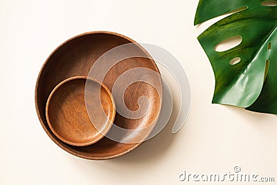 Wooden plates and monstera leaf flat lay composition. Empty dishes on light beige background, top view. Mockup for menu or recipe Stock Photo