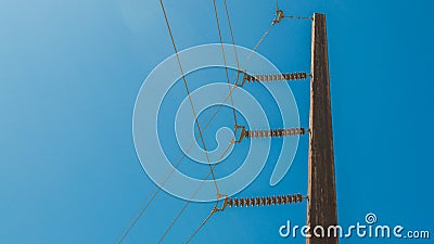 Wooden pole with heavy electrical cables under bright blue sky Stock Photo