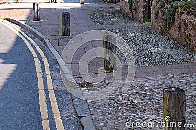 Wooden posts set in the pavement at Nether Stowey in Somerset to prevent cars parking or driving on the pavement Stock Photo