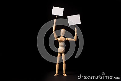 Wooden puppet with a poster or banner in their hands on a black background Stock Photo